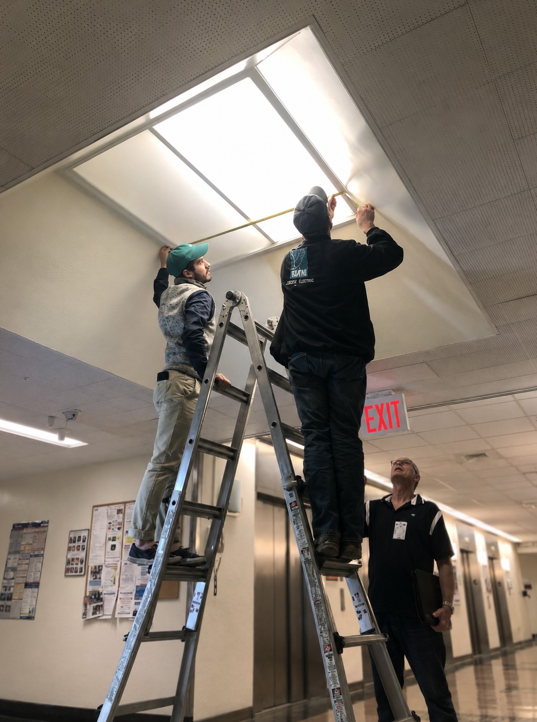 Renova technicians measuring and installing LED fixtures on-site at Bellevue